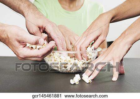 Close-up of hands taking popcorns from a bowl View Large Photo Image Stock Image - Close-up of hands taking popcorns from a bowl. Fotosearch