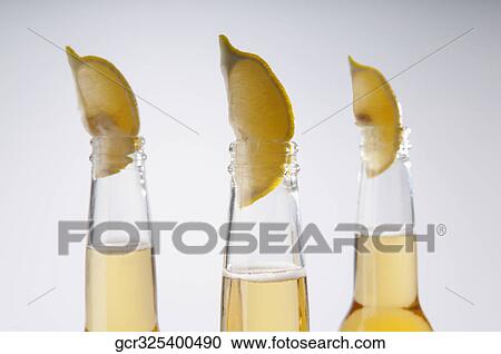 Stock Image - Close-up of lemon wedges in beer bottles. Fotosearch