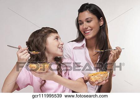 Close-up of mother and daughter eating cereal View Large Photo Image Stock Photo - Close-up of mother and daughter eating cereal. Fotosearch