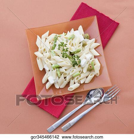 Stock Image - Close-up of pasta in a plate with tableware. Fotosearch