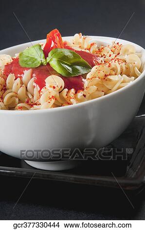 Picture - Close-up of rotini pasta topped with tomato sauce and basil. Fotosearch