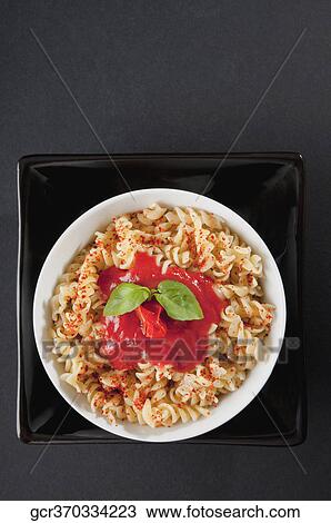 Stock Image - Close-up of rotini pasta topped with tomato sauce and basil. Fotosearch