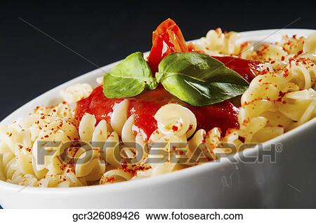 Stock Photograph - Close-up of rotini pasta topped with tomato sauce and fresh basil. Fotosearch