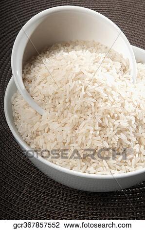 Stock Image - Close-up of uncooked rice in ceramic bowls. Fotosearch