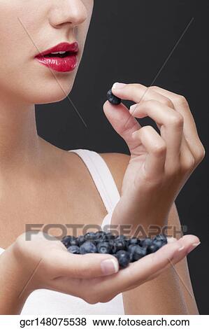 Stock Photo - Close-up of woman eating blueberries. Fotosearch