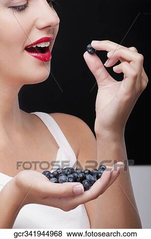 Stock Photo - Close-up of woman eating blueberries. Fotosearch