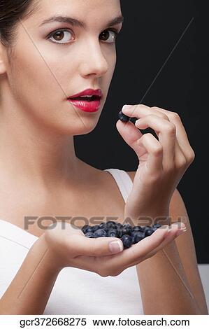 Stock Photography - Close-up of woman eating blueberries. Fotosearch
