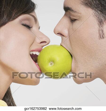 Couple biting into a green apple View Large Photo Image Stock Image - Couple biting into a green apple. Fotosearch