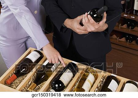 Couple choosing wine bottles in a bar View Large Photo Image Stock Photo - Couple choosing wine bottles in a bar. Fotosearch