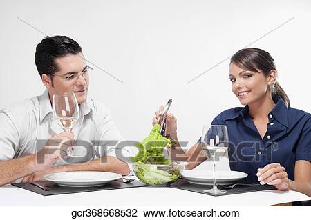 Stock Image - Couple having vegetable salad and drinking white wine. Fotosearch