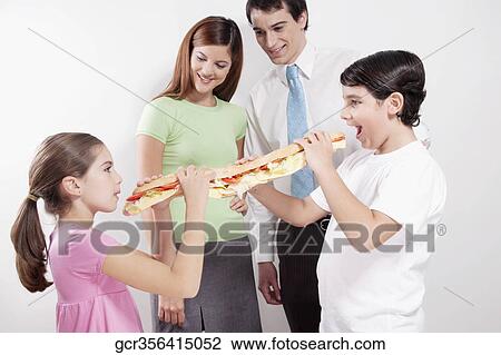 Couple looking at their son and daughter sharing a submarine sandwich View Large Photo Image Stock Image - Couple looking at their son and daughter sharing a submarine sandwich. Fotosearch