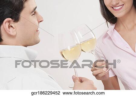 Stock Image - Couple toasting glasses of wine and smiling. Fotosearch