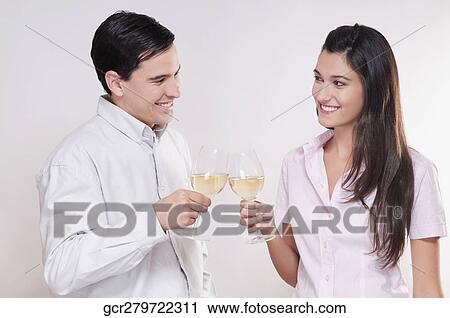 Couple toasting glasses of wine and smiling View Large Photo Image Stock Image - Couple toasting glasses of wine and smiling. Fotosearch