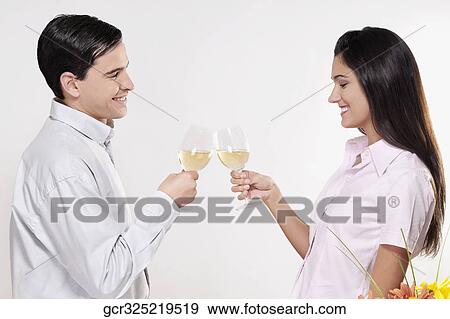 Stock Photo - Couple toasting glasses of wine and smiling. Fotosearch
