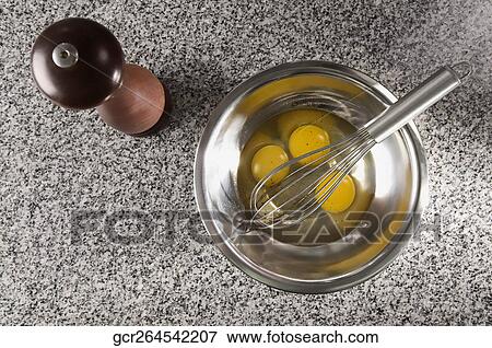 Egg yolk with a wire whisk in a bowl next to a pepper mill View Large Photo Image Stock Photo - Egg yolk with a wire whisk in a bowl next to a pepper mill. Fotosearch
