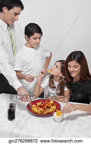 Family eating nachos with salsa View Large Photo Image Stock Image - Family eating nachos with salsa. Fotosearch