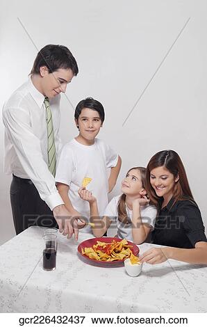 Family eating nachos with salsa View Large Photo Image Stock Photo - Family eating nachos with salsa. Fotosearch