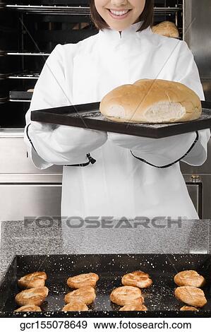 Stock Photo - Female chef holding a bun in a tray. Fotosearch