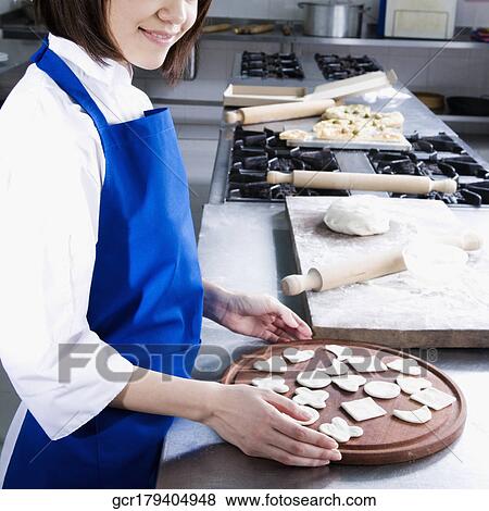 Stock Photo - Female chef making cookies in the kitchen. Fotosearch