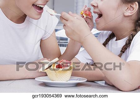 Girl and a teenage girl feeding ice cream to each other View Large Photo Image Stock Photo - Girl and a teenage girl feeding ice cream to each other. Fotosearch