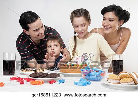 Girl blowing out birthday candles with their family View Large Photo Image Stock Image - Girl blowing out birthday candles with their family. Fotosearch
