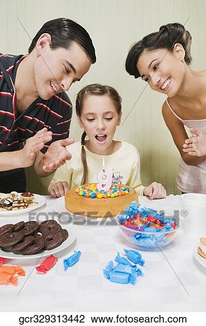 Stock Image - Girl celebrating her birthday with her parents. Fotosearch