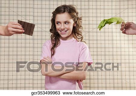 Girl choosing between a chocolate and a lettuce leaf View Large Photo Image Stock Image - Girl choosing between a chocolate and a lettuce leaf. Fotosearch