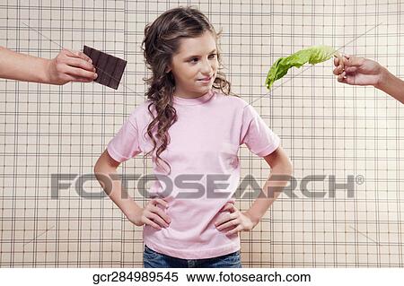 Stock Photography - Girl choosing between a chocolate and a lettuce leaf. Fotosearch