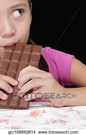 Picture - Girl eating a bar of chocolate. Fotosearch