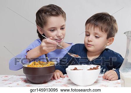 Stock Photography - Girl feeding cereal to her brother. Fotosearch