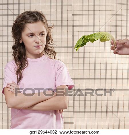 Girl frowning at a lettuce leaf View Large Photo Image Stock Image - Girl frowning at a lettuce leaf. Fotosearch