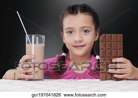 Stock Photograph - Girl holding a bar of chocolate and a glass of chocolate milkshake. Fotosearch
