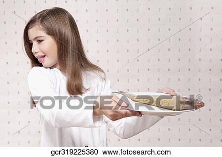Stock Image - Girl holding a raw fish on a plate and making a disgust face. Fotosearch