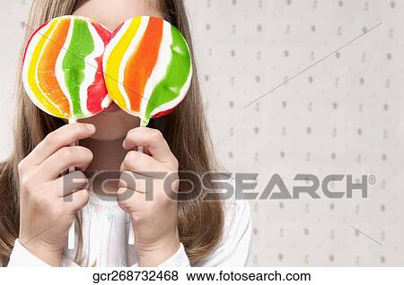 Girl holding lollipops in front of her eyes View Large Photo Image Stock Photo - Girl holding lollipops in front of her eyes. Fotosearch