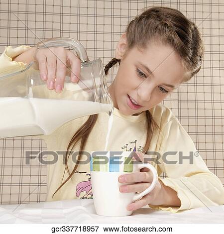 Girl pouring milk into a cup View Large Photo Image Stock Photo - Girl pouring milk into a cup. Fotosearch