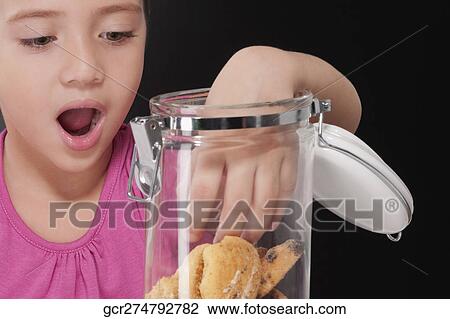 Stock Image - Girl putting her hand into a cookie jar. Fotosearch