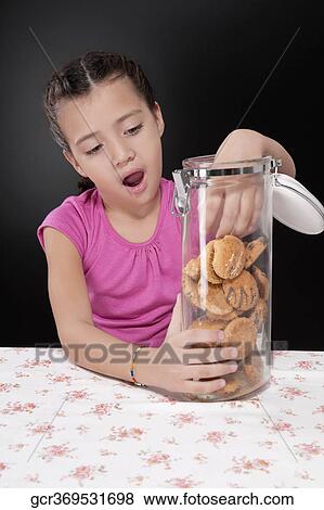Girl putting her hand into a cookie jar View Large Photo Image Stock Photo - Girl putting her hand into a cookie jar. Fotosearch
