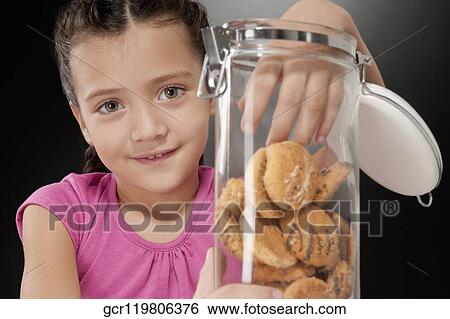 Girl putting her hand into a cookie jar View Large Photo Image Stock Photograph - Girl putting her hand into a cookie jar. Fotosearch