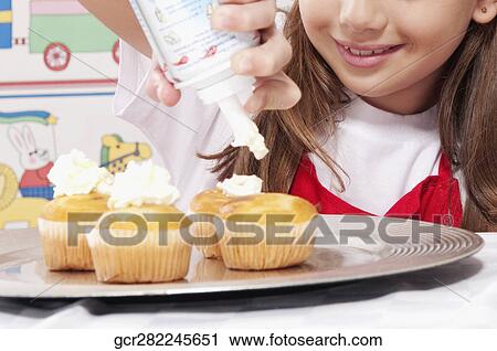 Girl putting whipped cream on cupcakes View Large Photo Image Stock Image - Girl putting whipped cream on cupcakes. Fotosearch