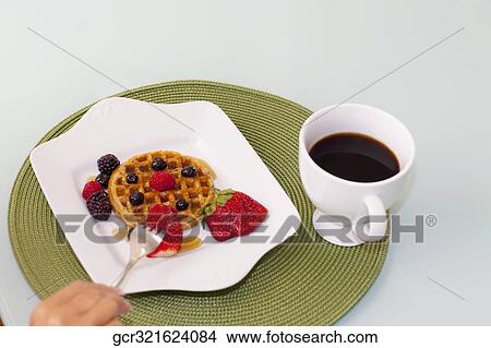 High angle view of a person eating a strawberry with waffles View Large Photo Image Picture - High angle view of a person eating a strawberry with waffles. Fotosearch
