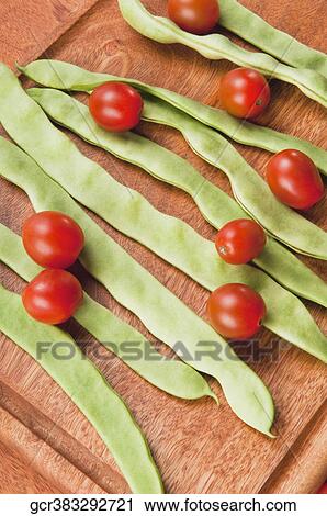 Stock Image - High angle view of beans with cherry tomatoes on a cutting board. Fotosearch