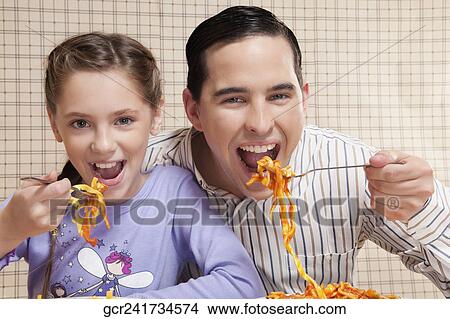 Man and his daughter eating pasta View Large Photo Image Picture - Man and his daughter eating pasta. Fotosearch