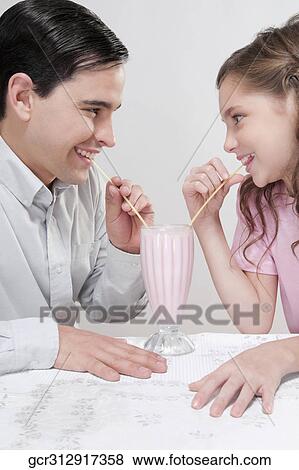 Stock Photo - Man and his daughter sharing a milkshake. Fotosearch