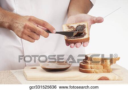 Man applying chocolate sauce on a slice of bread View Large Photo Image Stock Photograph - Man applying chocolate sauce on a slice of bread. Fotosearch
