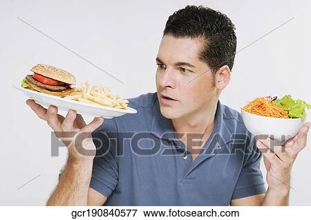 Man choosing between a hamburger plate and a salad bowl View Large Photo Image Stock Photo - Man choosing between a hamburger plate and a salad bowl. Fotosearch