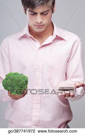 Man choosing between broccoli and chocolate View Large Photo Image Stock Image - Man choosing between broccoli and chocolate. Fotosearch