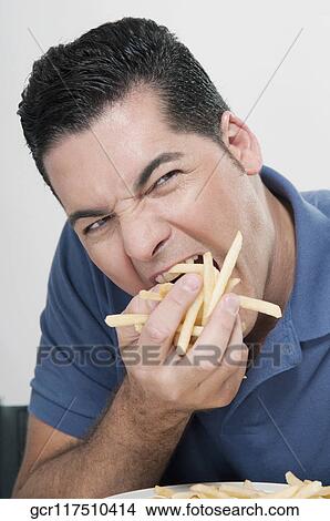 Man eating a fistful of fries View Large Photo Image Picture - Man eating a fistful of fries. Fotosearch