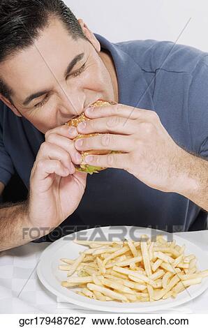 Stock Photo - Man eating a hamburger. Fotosearch