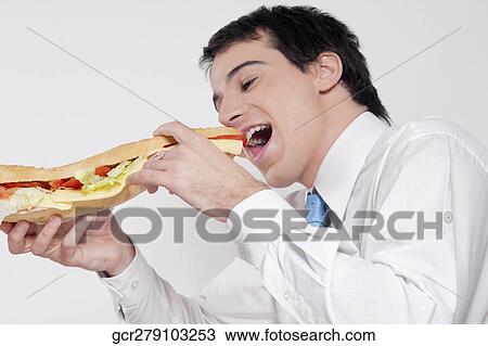 Stock Image - Man eating a submarine sandwich. Fotosearch