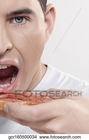 Picture - Man eating jam on toast. Fotosearch